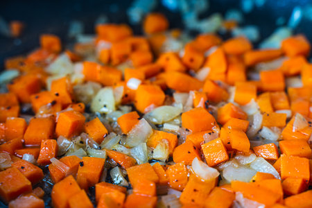 Diced carrots and onions are fried in a pan. Background with the texture of roasted vegetables. High quality photoの写真素材