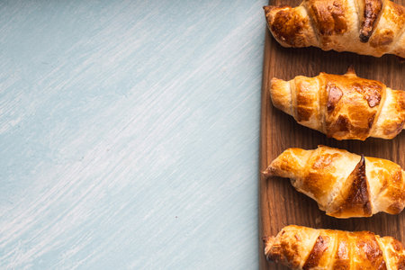 Croissants on a wooden board on a blue background. Copyspace, place for text. High quality photoの写真素材