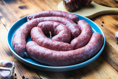 Raw homemade sausage on a blue plate on a wooden table or garlic background. High quality photoの写真素材