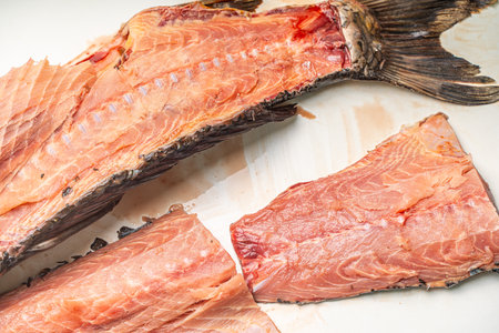Raw carp fish cut on the table for further cooking. Red fish fillet on a white background. Cutting...