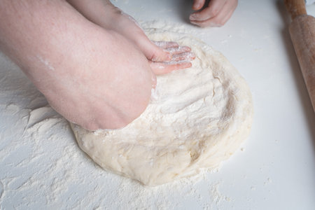 The hands of a man and a child in flour make a pie or pizza from dough. The concept of family relationships, support and love. Spending time together and hobbies. High quality photoの写真素材