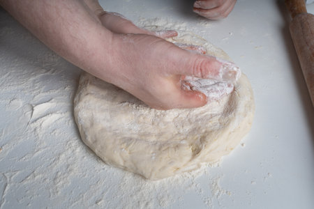 The hands of a man and a child in flour make a pie or pizza from dough. The concept of family relationships, support and love. Spending time together and hobbies. High quality photoの写真素材