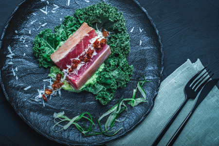 Tuna served with mashed potatoes, kale salad, sun-dried tomatoes and cheese on a black plate, background. Original, restaurant serving of fish. Dietary Nutrition Concept.Top view. High quality photoの写真素材