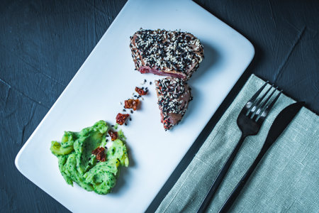 Raw tuna slices with black and white sesame seeds on a black background. High quality photoの写真素材
