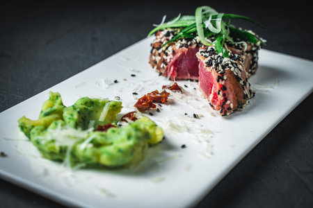 Raw tuna slices with black and white sesame seeds on a black background. High quality photoの写真素材