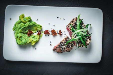 Raw tuna slices with black and white sesame seeds on a black background. High quality photoの写真素材