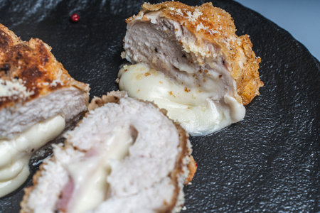 Cordon Bleu chicken cutlet with bacon and cheese on a black plate. Close-up. High quality photoの写真素材