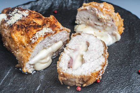 Cordon Bleu chicken cutlet with bacon and cheese on a black plate. Close-up. High quality photoの写真素材