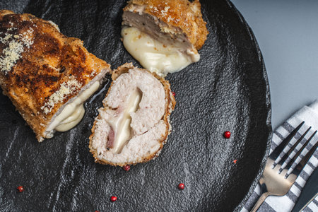 Cordon Bleu chicken cutlet with bacon and cheese on a black plate. Close-up. Top view. High quality photoの写真素材