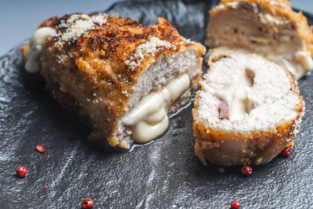 Cordon Bleu chicken cutlet with bacon and cheese on a black plate. Close-up. High quality photo