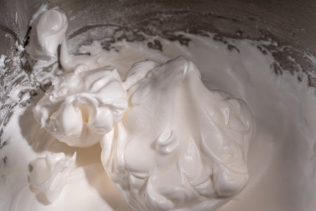 Whipped raw egg white or meringue in a steel bowl of a stand mixer. Place for text. Background with the texture of whipped protein with sugar. Close-up. High quality photoの写真素材