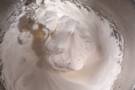 Whipped raw egg white or meringue in a steel bowl of a stand mixer. Place for text. Background with the texture of whipped protein with sugar. Close-up. High quality photoの写真素材