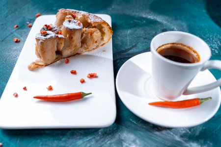 Tarte Tatin a French banana dessert, a slice of cake on a white plate with freeze-dried raspberries and chili peppers, a cup of coffee on a dark green background. Space for text,. High quality photoの写真素材