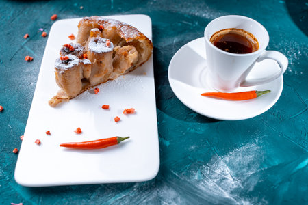 Tarte Tatin a French banana dessert, a slice of cake on a white plate with freeze-dried raspberries and chili peppers, a cup of coffee on a dark green background. Space for text,. High quality photoの写真素材