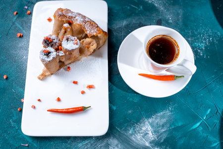 Tarte Tatin a French banana dessert, a slice of cake on a white plate with freeze-dried raspberries and chili peppers, a cup of coffee on a dark green background. Space for text,. High quality photoの写真素材