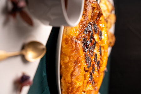 Traditional homemade banana caramel pie. French Tarte Tatin on a white plate with a cup of tea on a green, emerald background. Top view. Close-up. High quality photoの写真素材