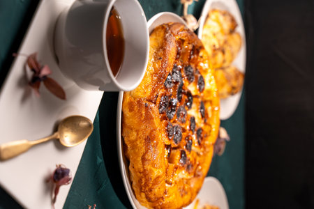 Traditional homemade banana caramel pie. French Tarte Tatin on a white plate with a cup of tea on a green, emerald background. Top view. Close-up. High quality photoの写真素材