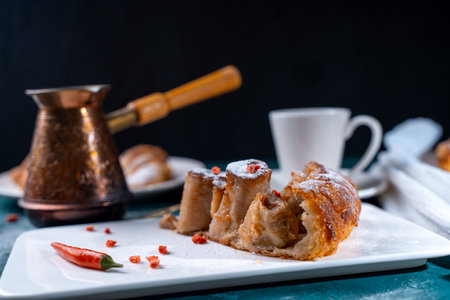 A slice of banana pie with hot chili peppers and coffee cooked in a cezve on a dark green background. French Tarte Tatin and handmade croissants on the table. High quality photoの写真素材