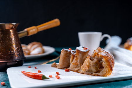 A slice of banana pie with hot chili peppers and coffee cooked in a cezve on a dark green background. French Tarte Tatin and handmade croissants on the table. High quality photoの写真素材