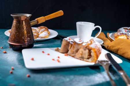 Banana dessert Tarte tatin and croissants on a dark green background with a cup of coffee brewed in a cezve and freeze-dried raspberries. High quality photoの写真素材