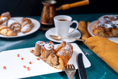 Banana dessert Tarte tatin and croissants on a dark green background with a cup of coffee brewed in a cezve and freeze-dried raspberries. High quality photoの写真素材