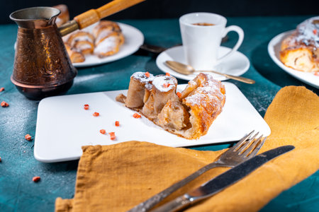 Banana dessert Tarte tatin and croissants on a dark green background with a cup of coffee brewed in a cezve and freeze-dried raspberries. High quality photoの写真素材