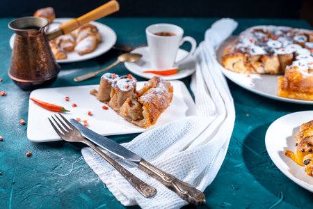 A slice of banana pie with hot chili peppers and coffee cooked in a cezve on a dark green background. French Tarte Tatin and handmade croissants on the table. High quality photoの写真素材
