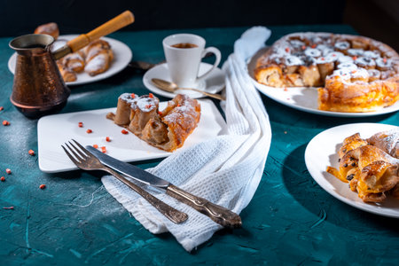Banana dessert Tarte tatin and croissants on a dark green background with a cup of coffee brewed in a cezve and freeze-dried raspberries. High quality photoの写真素材