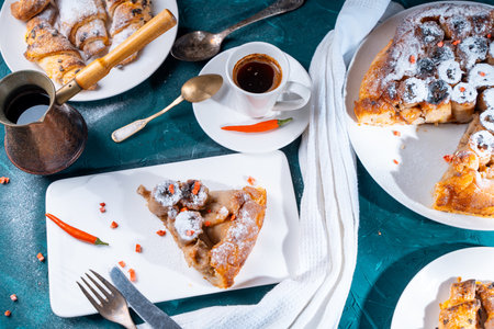 A slice of banana pie with hot chili peppers and coffee cooked in a cezve on a dark green background. French Tarte Tatin and handmade croissants on the table. High quality photoの写真素材