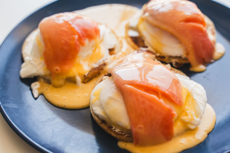 Eggs Benedict with salmon and hollandaise sauce on a blue plate. Concept: a delicious and healthy breakfast. High quality photoの写真素材