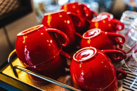 Many ceramic red coffee cups on a coffee machine shelf in a cafe. Selective focus. Red coffee cups on a shelf in a cafe, second row of selective red cup with soft focus. High quality photoの写真素材