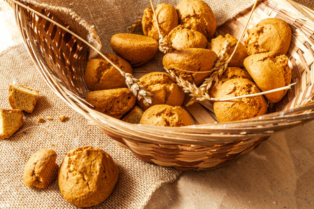 Freshly baked buns in a wicker basket with ears of wheat. Close-up. Selected focus. High quality...