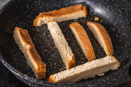 Slices of bread or croutons are toasted in a black pan. High quality photoの写真素材