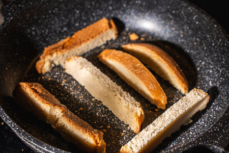 Slices of bread or croutons are toasted in a black pan. High quality photoの写真素材