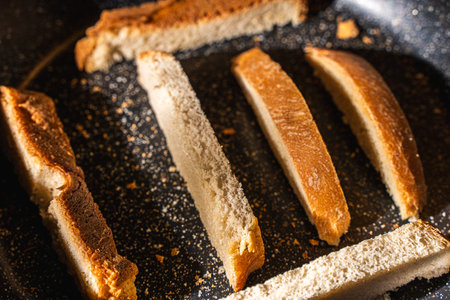 Slices of bread or croutons are toasted in a black pan. High quality photoの写真素材