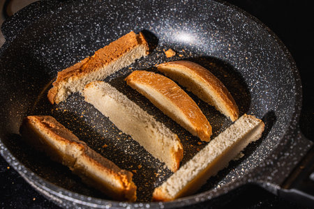 Slices of bread or croutons are toasted in a black pan. High quality photoの写真素材