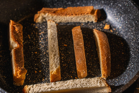 Slices of bread or croutons are toasted in a black pan. High quality photoの写真素材