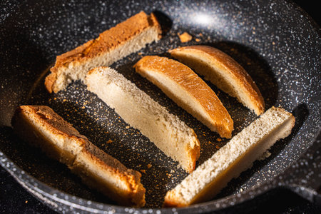 Slices of bread or croutons are toasted in a black pan. High quality photoの写真素材