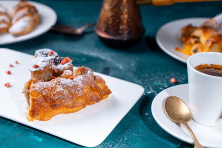 A piece of banana cake or pie and a cup of coffee on a white plate on a turquoise background....