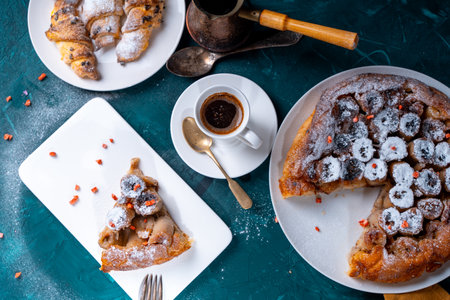 Banana tarte Tatin on a turquoise table with coffee brewed in a cezve and croissants. A slice of French dessert garnished with freeze-dried strawberries. View from above. High quality photoの写真素材