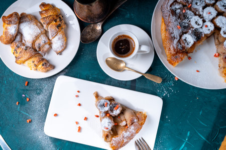 Banana tarte Tatin on a turquoise table with coffee brewed in a cezve and croissants. A slice of French dessert garnished with freeze-dried strawberries. View from above. High quality photoの写真素材