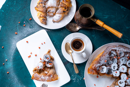 Banana tarte Tatin on a turquoise table with coffee and croissants. A slice of French dessert garnished with freeze-dried strawberries. View from above. High quality photoの写真素材