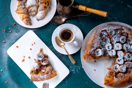 Banana tarte Tatin on a turquoise table with coffee and croissants. A slice of French dessert garnished with freeze-dried strawberries. View from above. High quality photoの写真素材