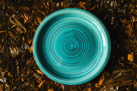 Turquoise plate empty on brown with gold background. Top view, space for text. High quality photoの写真素材