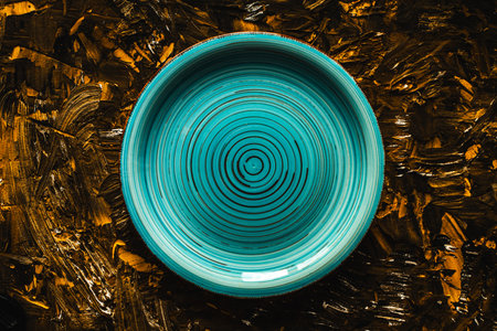 Turquoise plate empty on brown with gold background. Top view, space for text. High quality photoの写真素材