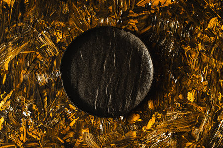 A black mica plate is empty on a brown gold background. Top view, flat layout, close-up.の写真素材