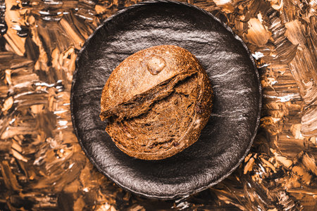 Rye bread or bun on a black mica board on a brown textured background. Close-up. Space for text. High quality photoの写真素材