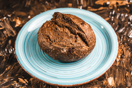 A loaf of rye bread on a turquoise or blue plate on a brown background. Close-up. Top view, Space for text. High quality photoの写真素材