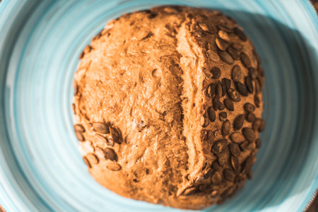 A loaf of rye bread on a turquoise or blue plate on a brown background. Close-up. Top view, Space for text. High quality photoの写真素材