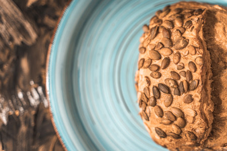 A loaf of rye bread on a turquoise or blue plate on a brown background. Close-up. Top view, Space for text. High quality photoの写真素材